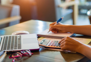 woman working with calculator, business document and laptop comp